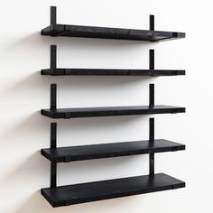 three black shelves on the wall with white walls and one shelf has two empty shelves