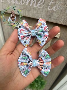 someone is holding two small bows in their hand, one with cartoon characters on it