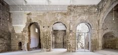 an empty room with stone walls and arched doorways in the center, surrounded by brick arches