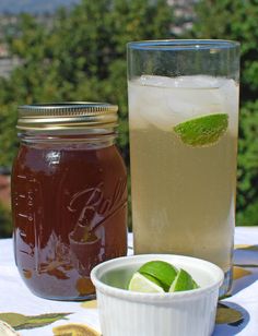 two glasses filled with liquid sitting on top of a table next to a bowl and jar