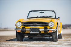 the front end of an old yellow convertible car