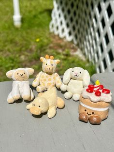 several small stuffed animals sitting on top of a wooden table in front of a fence