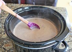 a wooden spoon in a slow cooker filled with chocolate