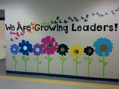 a wall with flowers painted on it that says we are growing leaders