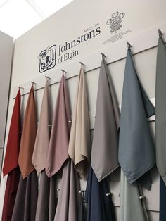 there are many different colored sheets hanging on the wall in front of it's logo