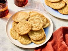 two white plates filled with cookies next to a glass of soda and an orange napkin