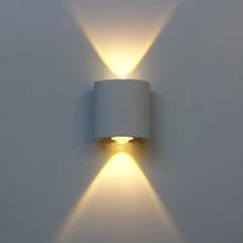 a white wall light that is on the side of a wall with two lights in it