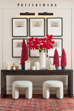 a table with red poinsettias and pictures on the wall