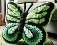 a crocheted butterfly sitting on top of a green rug next to a couch