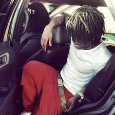 two people sitting in the back seat of a car, one with dreadlocks