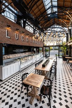 a restaurant with black and white checkered flooring, tables and benches in the center