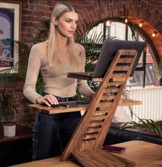 a woman standing in front of a laptop computer on a wooden desk with a ladder