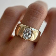 a close up of a person's hand wearing a gold ring with a diamond