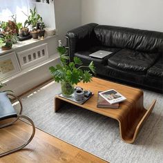 a living room with black leather couches and wooden coffee table in front of a window