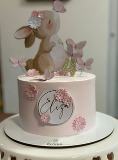 there is a pink cake decorated with flowers and a bunny on it's top