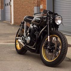 a black and gold motorcycle parked in front of a building with garage doors behind it