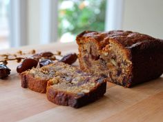 a sliced loaf of banana bread sitting on top of a wooden cutting board next to raisins