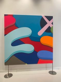 an abstract painting on display in a white room with two round pedestals underneath it