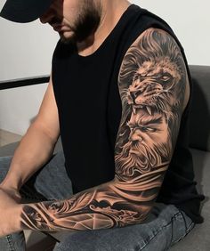 a man with a lion tattoo on his arm is sitting in front of a laptop