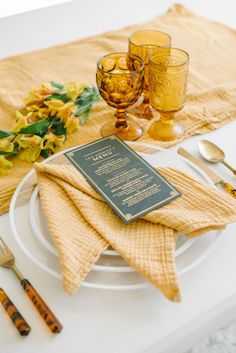 a place setting with napkins, glasses and utensils on a white table