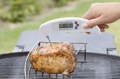 a person is using an electronic meat thermometer to cook a chicken on a grill