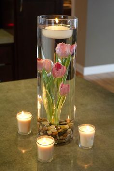 candles and flowers in a glass vase on a table