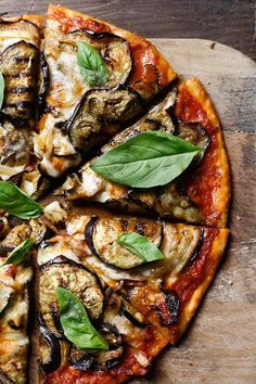 a pizza with an assortment of toppings and leaves on it sitting on a cutting board