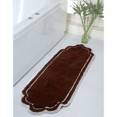 a bath mat on the floor in front of a white tub and window with green plants