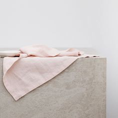 a folded pink cloth sitting on top of a cement block in front of a white wall