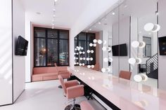 a salon with pink chairs and mirrors in front of large windows that have lights on them