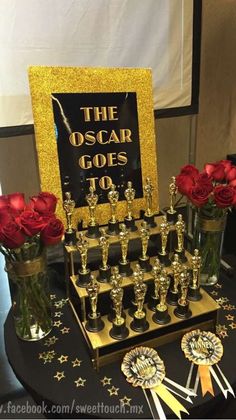 the oscars table is set up with red roses in vases and an award plaque