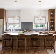 a kitchen with wooden cabinets and stools next to a center island in the middle