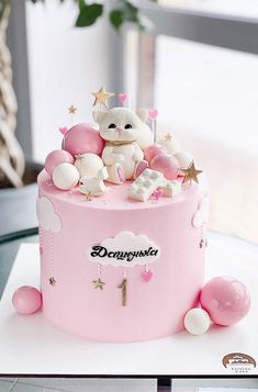 there is a pink cake decorated with teddy bears and stars on it's top