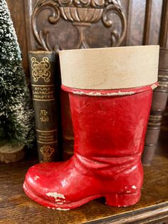 a pair of red rubber boots sitting on top of a wooden table next to books