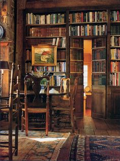 a room with many bookshelves full of books and chairs around a dining table