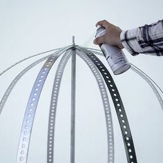 a person spray painting a metal sculpture with white and gray paint on it's sides