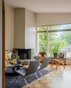 a living room filled with furniture and a fire place in front of a large window