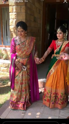 two women dressed in colorful sari standing next to each other on the steps outside of a house