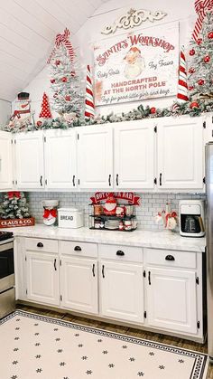 a kitchen with white cabinets and christmas decorations on the wall above the stove top oven