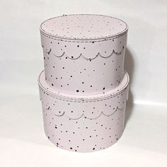 three round cake boxes are stacked on top of each other, one is white and the other has black speckles