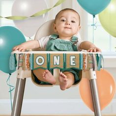 a baby sitting in a high chair with balloons around him and the word one on it