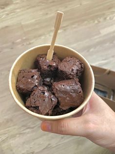 a hand holding a bowl filled with brownies