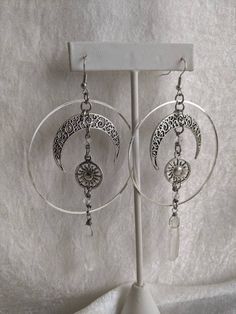 A gorgeous pair of earrings, featuring filigree crescent moons and sun charms with natural quartz columns dangling from the ends. Perfect for everyday to bring earth's surrounding mystical celestial bodies anywhere you go! Sun And Moon Design Moon Shaped Earrings For Festival, Spiritual Sun And Moon Design Earrings For Festival, Festival Metal Earrings With Moon Charm, Bohemian Sun And Moon Design Earrings For Festival, Moon Shaped Sun And Moon Design Festival Earrings, Crescent Moon Phase Earrings For Festivals, Mystical Moon Phase Earrings For Festivals, Festival Sun And Moon Dangle Jewelry, Bohemian Sun And Moon Earrings For Festivals