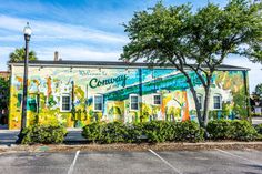 a large mural painted on the side of a building in a parking lot next to trees