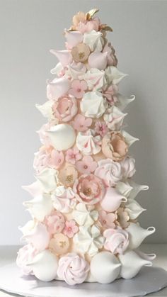 a pink and white cake with flowers on it's top tier, in the shape of a christmas tree