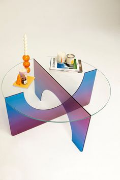 a glass coffee table with an abstract design on top and candles in the middle, sitting on a white surface