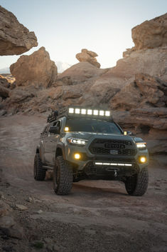 a truck with lights on driving through some rocks