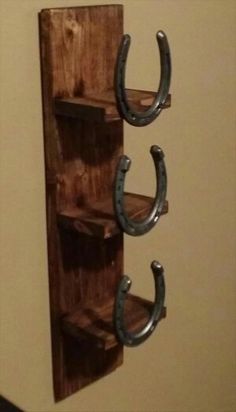 two horseshoes are hanging on the wall next to a wooden shelf with three hooks