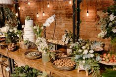 a table topped with lots of food next to a brick wall covered in greenery