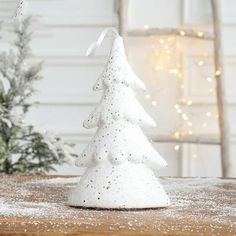 a small white christmas tree sitting on top of a wooden table